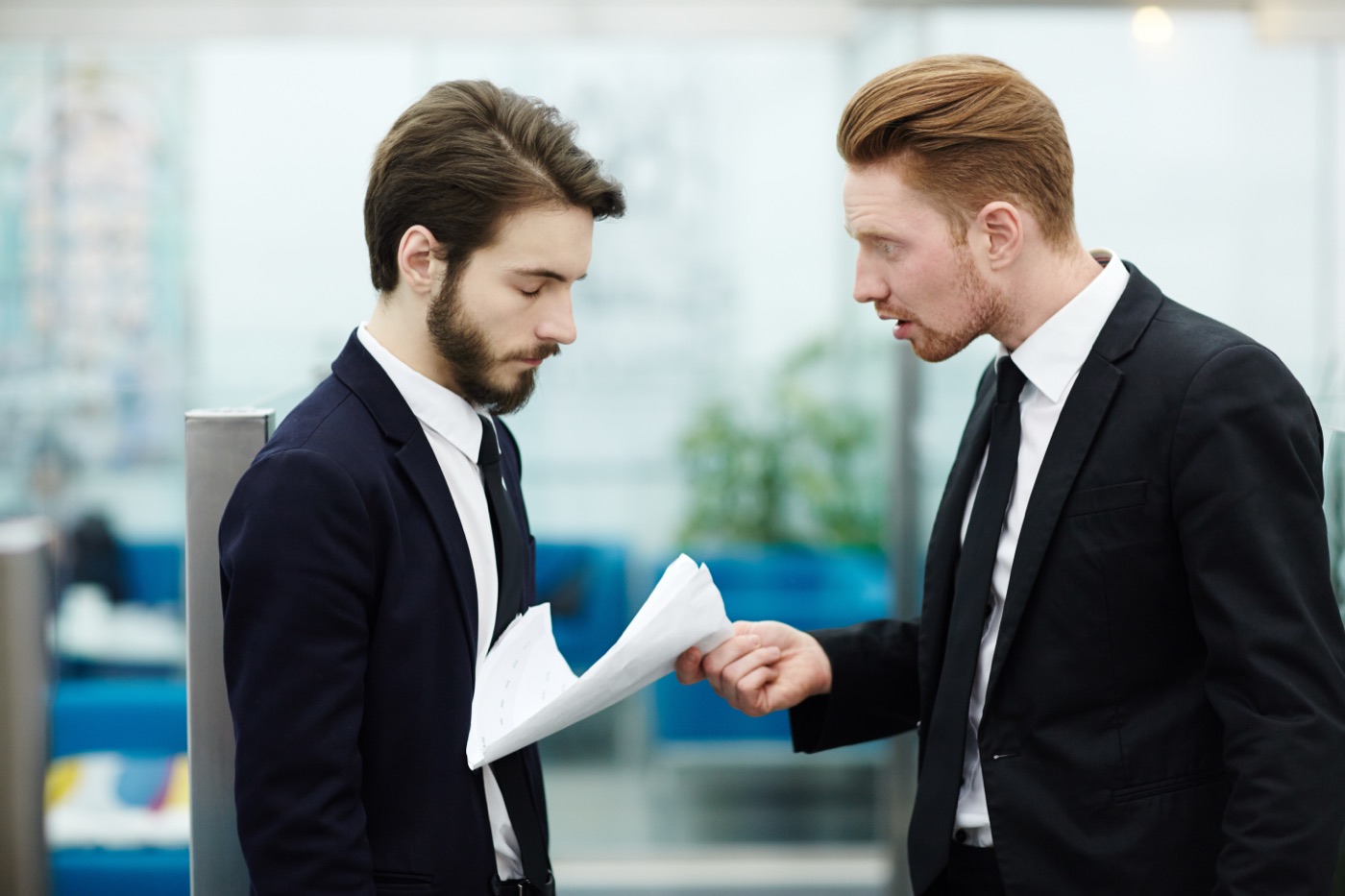 Two colleagues in suits reviewing documents together