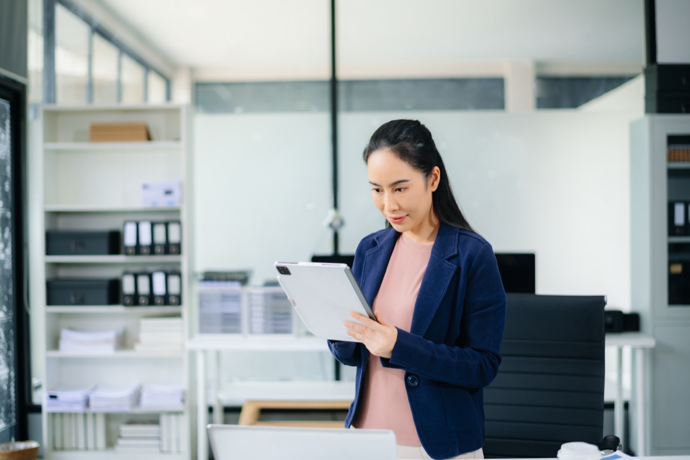 A procurement professional reviewing information on a tablet in a bright office